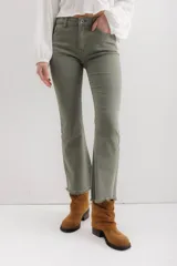 Pantalón de jean color marrón óxido, tiro medio, corte ajustado en muslos y ligeramente acampanado en la parte inferior (bootcut/flare), con bajo desflecado.