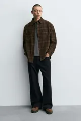 Zapato de cordones estilo trekking para hombre, confeccionado en piel con acabado de serraje color marrón. Presenta enganches metálicos para los cordones, cuello acolchado en color negro y una suela de goma con volumen y efecto moteado.