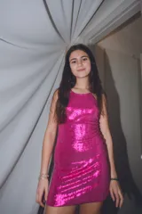 Vestido corto fucsia con lentejuelas, escote halter y espalda descubierta.