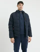 Campera capitoneada de poliéster color negro, con capucha desmontable, cierre frontal y bolsillo en el pecho con cierres engomados y tiradores en color naranja.