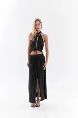 Top halter color bordó con tejido de lurex, escote con tiras cruzadas en el cuello y abertura frontal pronunciada con cordones ajustables.