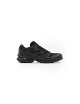 Championes Salomon modelo XT-6, diseñados para un estilo deportivo urbano. Presentan una estructura robusta en color negro con detalles técnicos, sistema de chasis ACS para estabilidad y amortiguación, y forro interior OrthoLite® para mayor comodidad.