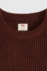 Sweater de punto con textura waffle, cuello redondo y mangas largas. Presenta un pequeño parche con logo en el puño izquierdo.