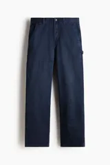Pantalón carpenter en sarga de algodón gruesa con cintura clásica y cierre con botón. Modelo con bolsillos al bies, bolsillos traseros y piernas rectas con costuras visibles sobre y bajo las rodillas. Cuenta con trabilla funcional en una pierna y bolsillo cargo con doble compartimento en la otra. Corte estándar para una silueta clásica y cómoda.