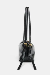 Bolso de hombro tipo baguette en color negro con acabado brillante. Presenta un diseño rectangular con cierre de cremallera superior y doble asa ajustable mediante hebillas metálicas.