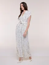 Enterito largo ABS Allen Schwartz de calce fluido, color blanco con diseño de rayas verticales negras. Presenta escote en V cruzado, mangas cortas, cintura definida con cinturón y hebilla ovalada, pantalón wide leg con bolsillos laterales y pinzas.