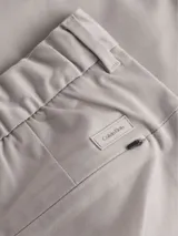 Pantalón de vestir color beige claro, de corte recto y ajuste regular, con cierre de botón y cremallera.