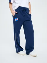 Pantalón de jogging azul marino con cordón ajustable en la cintura, bolsillos laterales y líneas blancas laterales. Presenta el escudo del Club Nacional de Football y el logo de Umbro bordados.