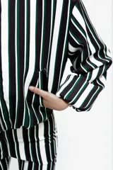 Campera tipo bomber corta, con cierre frontal, cuello a la base, bolsillos ojal y mangas largas abullonadas. Presenta un diseño estampado a rayas verticales en tonos blanco, negro y verde.