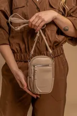 Bandolera compacta color rosado, con correa regulable y desmontable. Tiene apertura superior, bolsillo frontal con cierre y detalle de borla, y bolsillo trasero sin cierre. El interior está forrado en tela y cuenta con un bolsillo adicional.