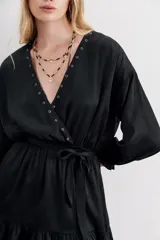 Vestido corto de estilo cruzado, color negro, con mangas largas abullonadas, puños elásticos y volado en el ruedo. Presenta un diseño de jacquard con corazones y cierre frontal con botones metálicos.