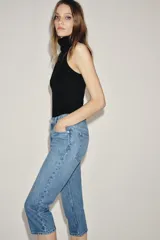 Jeans capri de tiro medio con diseño de cinco bolsillos, cintura con trabillas y cierre frontal con cremallera y botón. Presenta un acabado con efecto lavado.