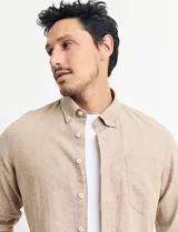 Camisa de manga larga confeccionada en una mezcla de algodón y lino, con cuello abotonado, bolsillo frontal en el pecho y cierre de botones.
