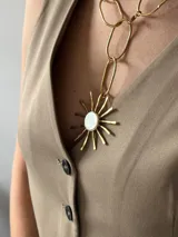 Collar con cadena de eslabones plateados y dije artesanal con forma de sol, con centro de nácar y rayos de alpaca.