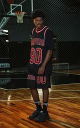 Bermuda deportiva negra de estilo NBA, confeccionada en tejido de punto deportivo. Presenta un elástico en la cintura con franjas rojas y blancas. Estampado frontal con la palabra "RAVERS" y el número "90" en rojo con borde blanco.