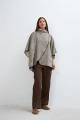Ruana color crudo de lana fina sin teñir, con capucha, bolsillos y terminaciones envivadas. Tiene un broche para usar cerrada. Es una prenda oversize sin forro, cómoda, versátil y fácil de combinar.