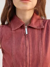 Enterito largo de denim color verde militar, sin mangas, con cuello camisero, cierre frontal completo y bolsillos laterales. Incluye cinturón ajustable del mismo material con hebilla metálica.
