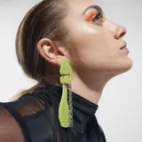 Aros colgantes con piezas geométricas de color verde lima unidas por argollas metálicas y cadenas plateadas.