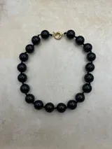 Collar de esferas negras de resina con cierre marinero dorado.