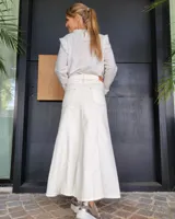 Pollera larga de corte recto en denim color arena, con diseño de cinco bolsillos, cierre frontal con botón y costuras a la vista.