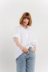 Blusa blanca de lino con escote en V abotonado y mangas cortas arremangadas.