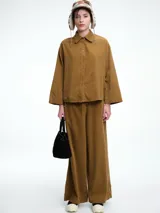 Camisa oversize de lyocell color tostado, con cuello clásico, cierre frontal de botones y mangas largas con puños anchos. Presenta un diseño de corte relajado con caída fluida.