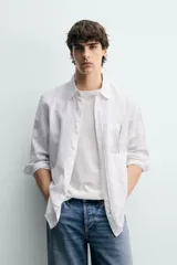 Camisa de corte regular fit en color azul, confeccionada en mezcla de lyocell y algodón, con cuello camisero, manga larga con puños abotonados, cierre frontal con botones y un bolsillo aplicado en el pecho.