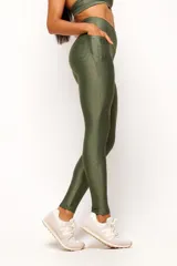 Calza deportiva de tiro alto en color verde militar, confeccionada en tejido técnico con acabado satinado. Presenta un diseño anatómico que se ajusta al cuerpo y cuenta con un bolsillo interno.