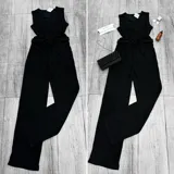 Mono largo negro de tejido arrugado con escote en V, sin mangas y corte holgado. Incluye cinturón de lazo en la cintura.