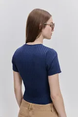 Top de manga corta color beige, confeccionado en tejido elastizado con textura acanalada, cuello redondo y calce al cuerpo.