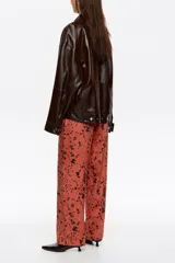 Pantalón de tiro medio y corte recto, con diseño estampado de manchas oscuras sobre base rojiza. Cuenta con cierre frontal de cremallera y corchete, bolsillos laterales y bolsillos traseros de vivo.