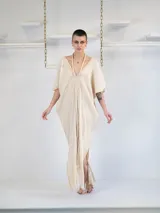 Vestido largo color crema, de corte holgado, escote en V con detalle trenzado y tajos laterales.