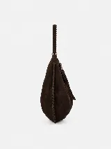 Bolso tipo hobo de gran tamaño, confeccionado en gamuza negra con detalles de costuras artesanales y tientos decorativos en los bordes. Cuenta con un asa trenzada con pespuntes a mano y cierre superior.