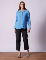 Camisa celeste con rayas verticales blancas, de corte clásico, cuello a la base, escote en V y abertura central con botones.