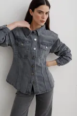Chaqueta de denim gris con corte entallado en la cintura, cuello camisero, cierre frontal con botones metálicos y bolsillos frontales con solapa.