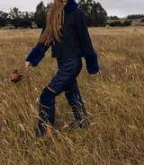 Pantalón de lana azul marino, de corte recto, con rodilleras de corderito en el mismo tono y detalles de ribetes tostados.