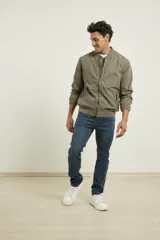 Campera tipo bomber color verde militar, confeccionada en 100% algodón. Cuenta con puños tejidos al tono, cuello y cintura elásticos, y cierre frontal metálico.