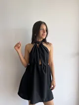 Vestido corto negro con escote halter y espalda descubierta. Presenta un corte a la cintura con falda acampanada.