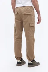 Pantalón cargo de corte relajado color tostado, con cintura elástica y cordón ajustable, bolsillos laterales tipo cargo y puños elásticos en los tobillos.
