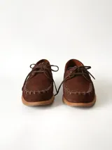 Sandalias de cuero gamuzado color marrón chocolate, diseño tipo huarache con tiras entrelazadas, tira en el empeine, talón cerrado y hebilla metálica de ajuste lateral.