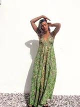 Vestido largo de estilo bohemio en color verde, con estampado paisley, escote en V profundo y breteles finos. Presenta detalles bordados con pedrería y espejos a lo largo del escote y el centro del frente, con una falda amplia y fluida.