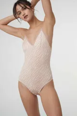 Body colaless de microfibra gloss con estampado de cebra en tonos beige y rosado. Presenta copas triangulares con bordes de puntilla, relleno extraíble, cierre en la entrepierna con broches de presión y breteles ajustables.