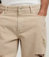 Bermuda masculina de sarga color beige con corte slim, diseño con roturas estilo destroyed y cierre tradicional de botón y cremallera.