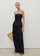 Top estilo corsé de mezclilla azul oscuro, sin mangas, con escote palabra de honor y corte peplum.