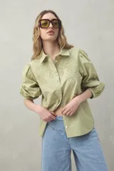 Camisa blanca de mangas 3/4 abullonadas con bordado floral en el frente.