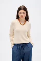 Sweater de tejido de punto fino en color blanco, con cuello redondo a la base y mangas largas de corte holgado.