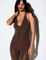 Mono largo de calce al cuerpo y acabado satinado, color marrón chocolate. Diseño con escote profundo tipo halter, tirantes finos y perneras ajustadas con aberturas en los tobillos.