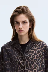 Campera de sarga de algodón con estampado animal print, cuello abierto, cierre frontal con botones y bolsillos delanteros de parche con solapa. Presenta hombros levemente caídos y puños abotonados.