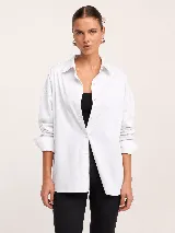 Camisa blanca de popelina oversize con cuello clásico, cierre frontal de botones y mangas largas con puños.