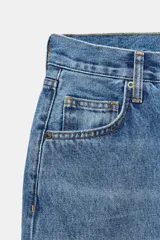 Jeans de tiro medio con corte baggy y pierna relajada. Presenta diseño de cinco bolsillos, cierre frontal con cremallera y botón, y bajo con vuelta marcada.
